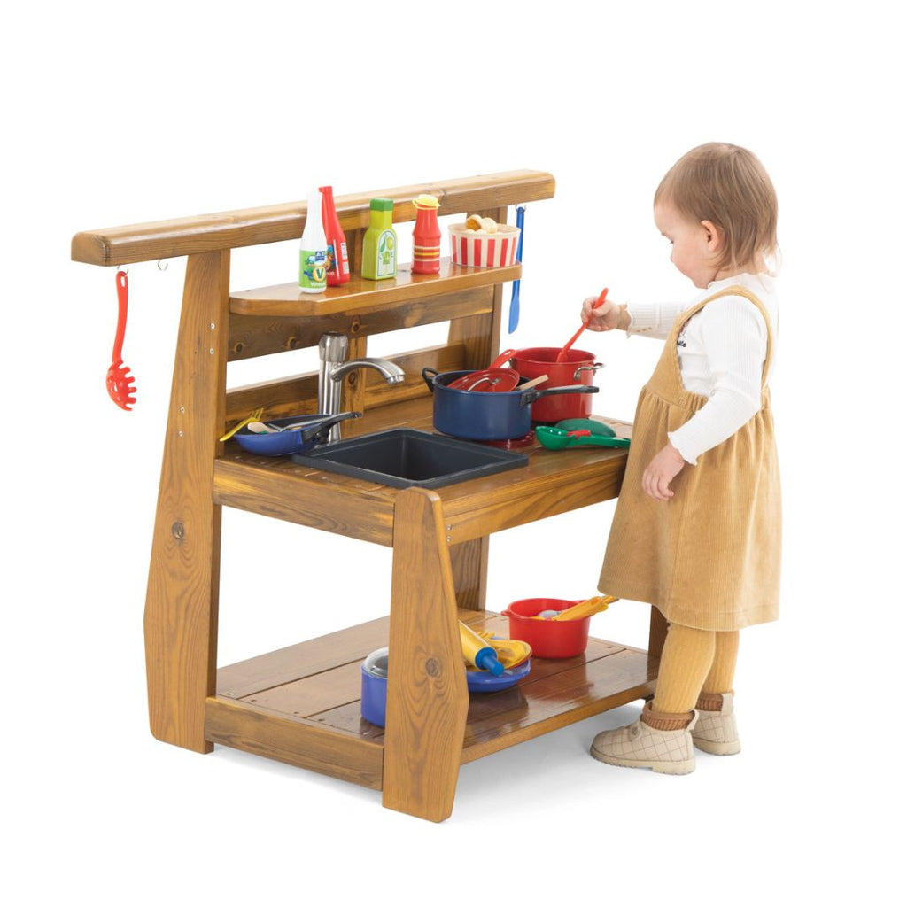 Peuters spelen met een houten buitenspeelkeuken met waterkraan, spoelbak en kookplaten. Ideaal buitenspeelgoed voor kinderdagverblijf of tuin, ontworpen voor kinderen onder de 3 jaar.