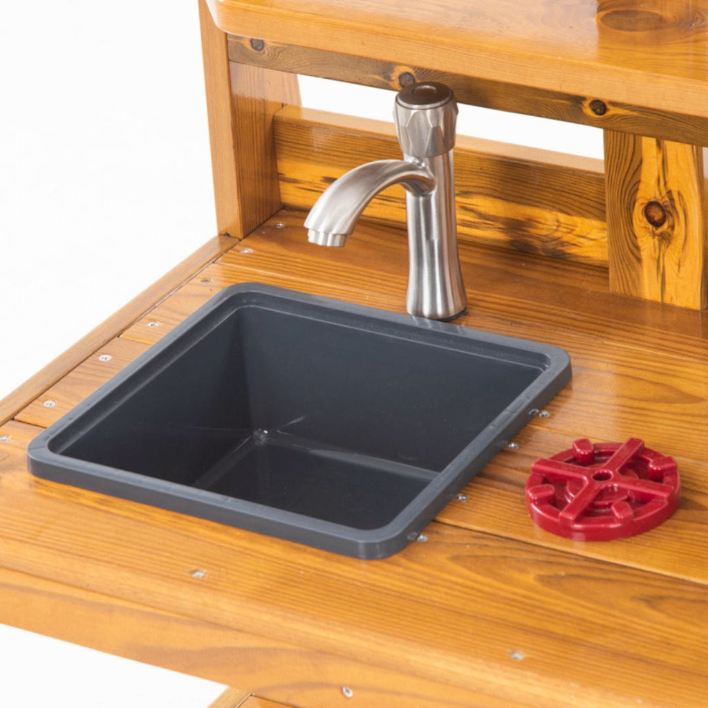 Peuters spelen met een houten buitenspeelkeuken met waterkraan, spoelbak en kookplaten. Ideaal buitenspeelgoed voor kinderdagverblijf of tuin, ontworpen voor kinderen onder de 3 jaar.